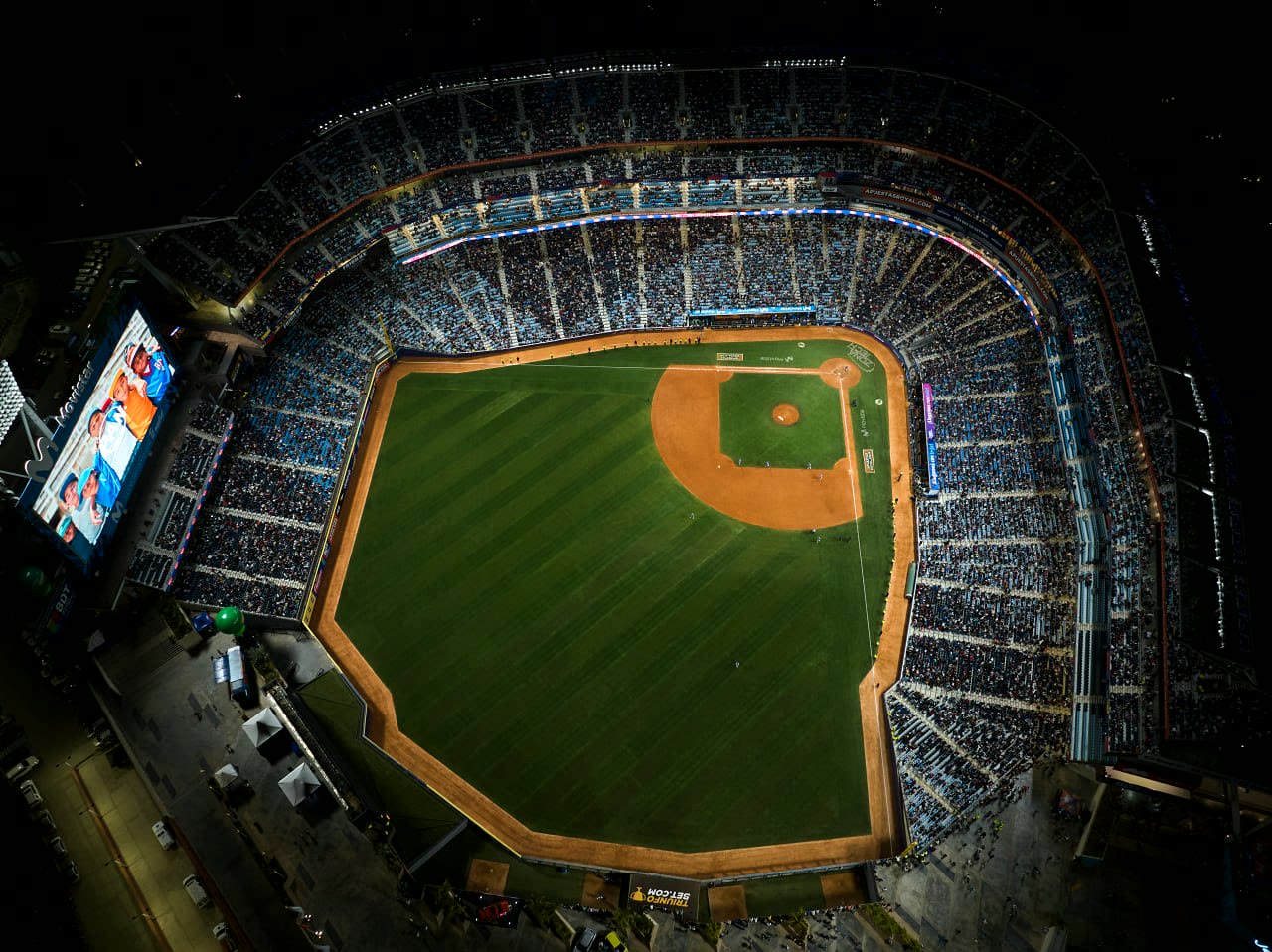 Vista aérea cenital de un estadio lleno durante un evento deportivo nocturno