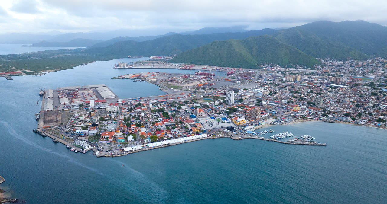 Vista aérea de un puerto, la costa y una zona urbana rodeada de montañas
